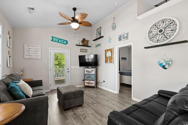 Living area with light wood finished floors, vaulted ceiling, baseboards, visible vents, and ceiling fan with notable chandelier | Image 16