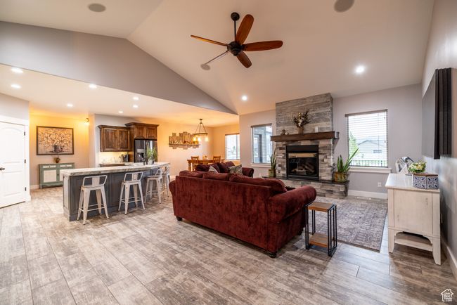 Living room with ceiling fan, light wood-style floors, a stone fireplace, recessed lighting, and high vaulted ceiling | Image 11