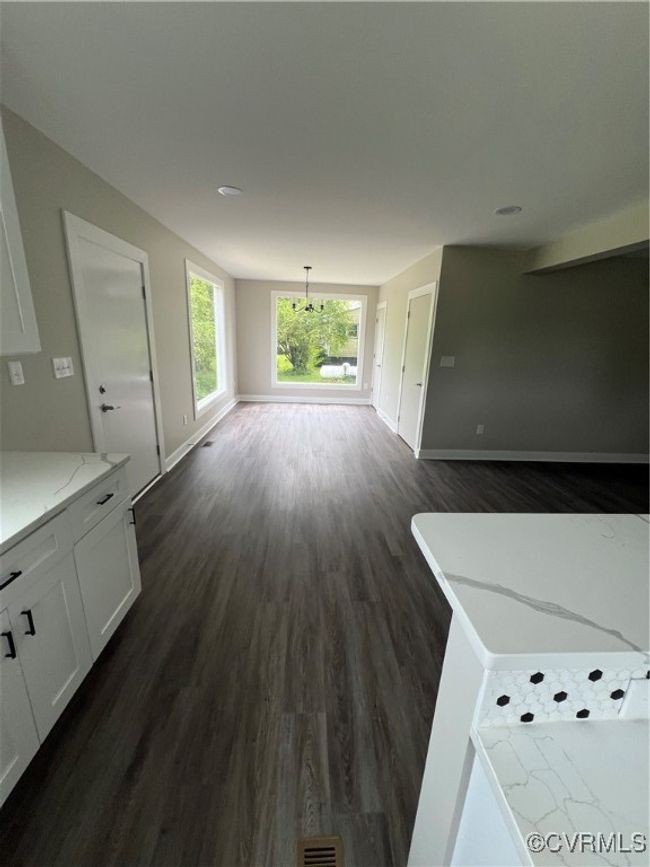 Unfurnished living room featuring baseboards and dark wood-style floors | Image 7
