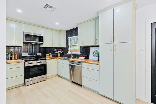 Kitchen featuring stainless steel appliances, butcher block countertops, tasteful backsplash, light wood-type flooring, and recessed lighting | Image 11