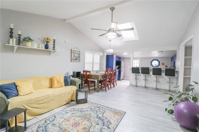 Living room with hardwood / wood-style flooring, lofted ceiling with skylight, and ceiling fan | Image 2