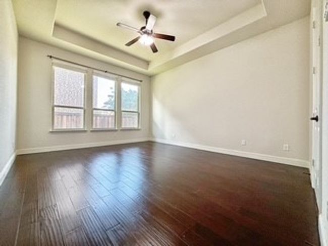Unfurnished room with a tray ceiling, dark wood-type flooring, and a ceiling fan | Image 14