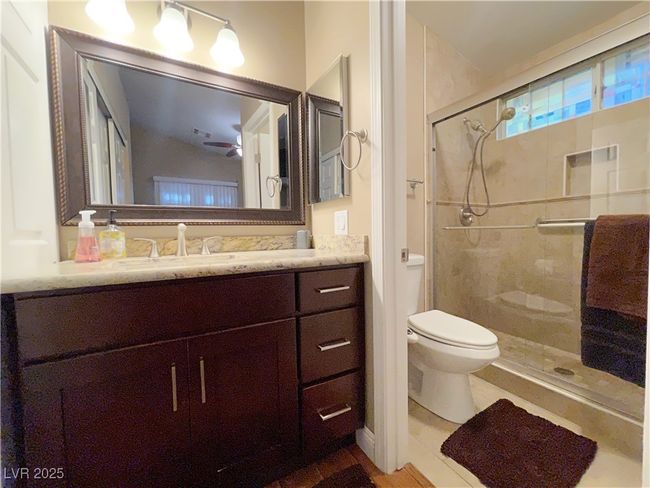 Full bathroom featuring toilet, a stall shower, vanity, and a ceiling fan | Image 17