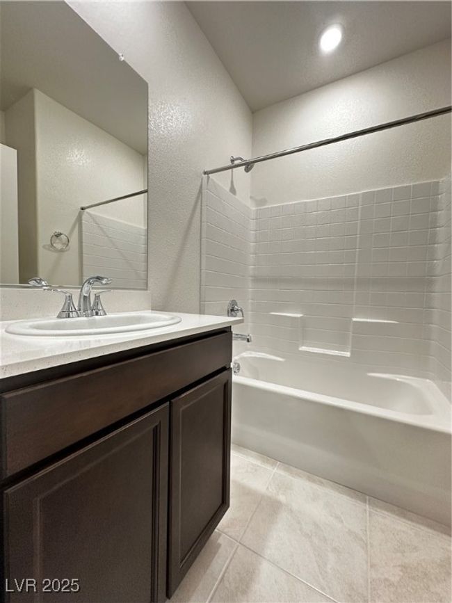Bathroom featuring a textured wall, shower / tub combination, vanity, and tile patterned floors | Image 9