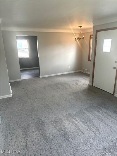 Carpeted spare room with a chandelier | Image 2