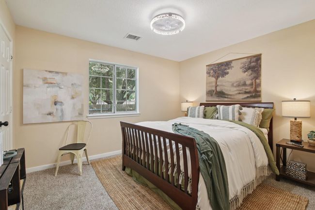 This cozy bedroom features soft beige walls and a large window for natural light. It includes modern lighting creating a warm and inviting atmosphere. | Image 23