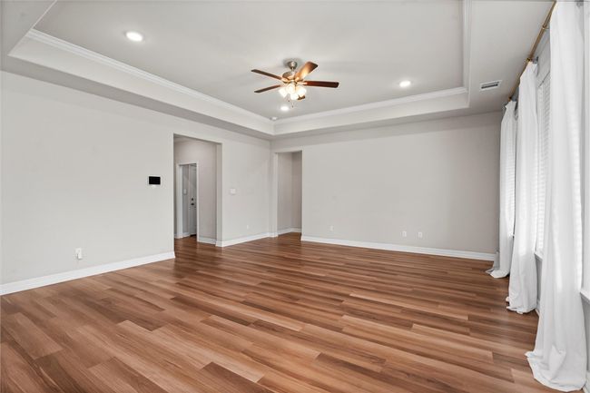 Unfurnished room featuring a tray ceiling, ceiling fan, crown molding, recessed lighting, and light wood-type flooring | Image 7
