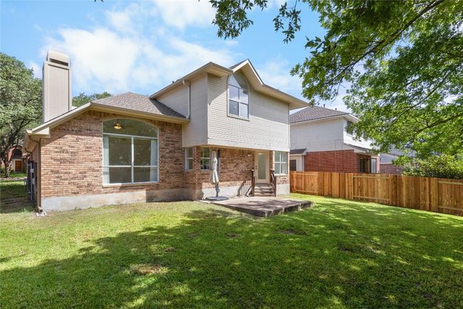 Rear view of property featuring brick siding, a chimney, roof with shingles, and a patio area | Image 26
