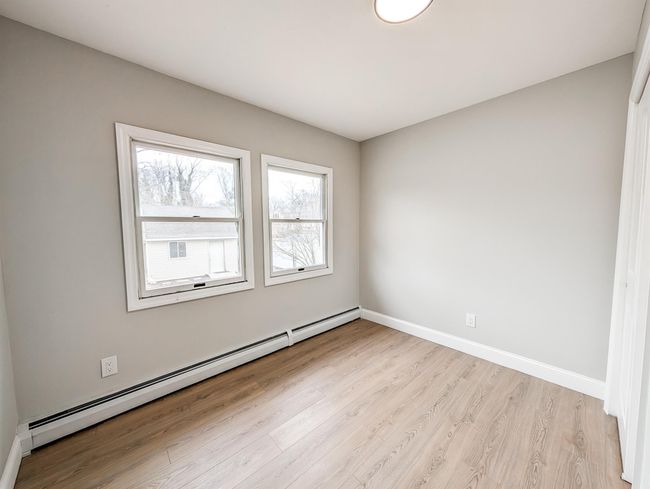 Empty room with baseboard heating, light wood-type flooring, and baseboards | Image 16
