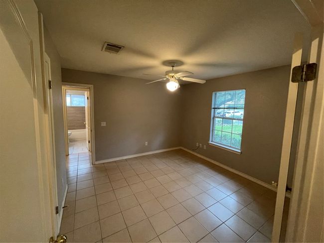 Empty room with light tile patterned floors and a ceiling fan | Image 14
