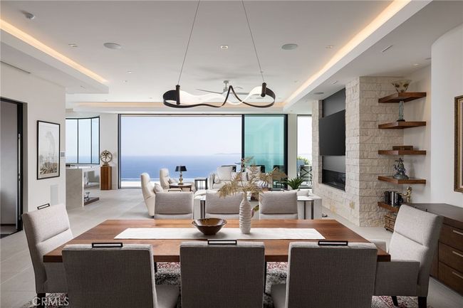The home's centerpiece is an expansive great room featuring 11.6’ ceilings, sliding glass doors, porcelain floors and custom 75” fireplace, all framing captivating sit-down ocean and pool vistas. | Image 8