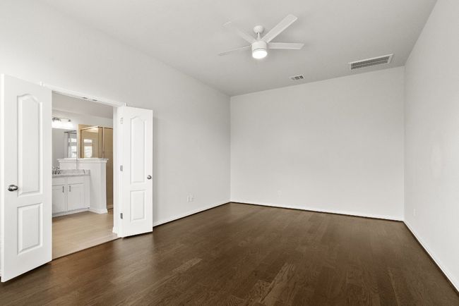 Unfurnished bedroom featuring wood finished floors, connected bathroom, and ceiling fan | Image 9