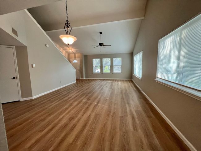 Unfurnished living room with ceiling fan, wood finished floors, and baseboards | Image 6