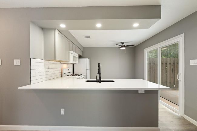 Kitchen featuring a sink, white appliances, a peninsula, backsplash, and recessed lighting | Image 14