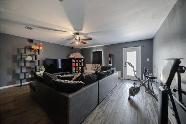 Living area with dark wood finished floors and a ceiling fan | Image 13