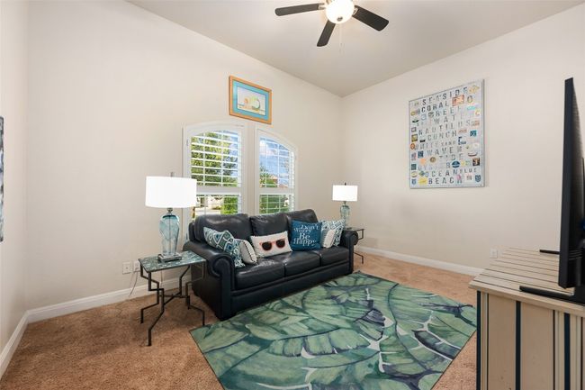 One of the two secondary bedrooms featuring a ceiling fan and plantation shutters. This bedroom faces the front of the home. | Image 19