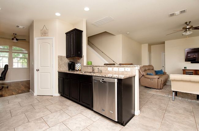 Kitchen with ceiling fan, stainless steel dishwasher, open floor plan, a peninsula, and a sink | Image 6