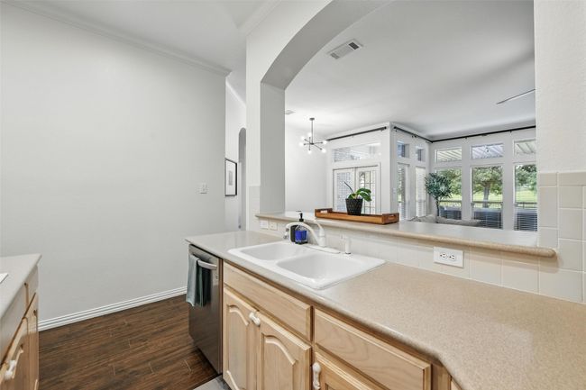Kitchen with dishwasher, arched walkways, dark wood-type flooring, a chandelier, and light brown cabinetry | Image 10