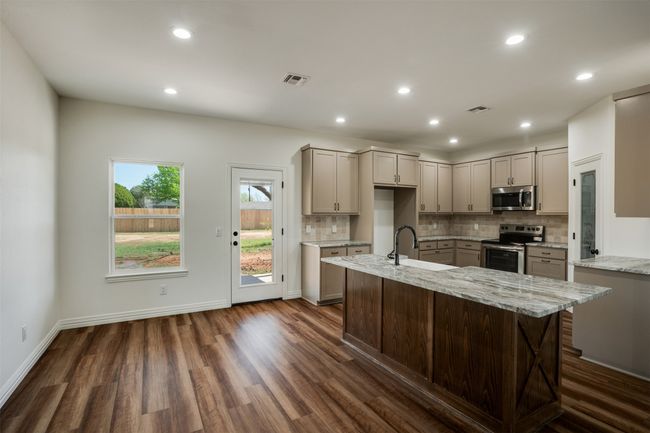 Kitchen featuring backsplash, dark wood finished floors, stainless steel appliances, and gray cabinetry | Image 7