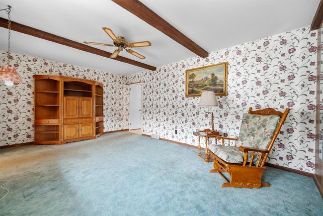 Unfurnished room featuring carpet, beamed ceiling, baseboards, and wallpapered walls | Image 8