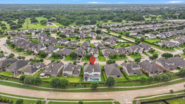 This aerial photo showcases a spacious suburban neighborhood with well-maintained homes, lush green lawns, and tree-lined streets. The highlighted property features a large backyard with a pool, offering a comfortable and inviting living environment. Ideal for families seeking a peaceful community setting. | Image 45