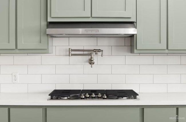 Details with stainless steel gas stovetop, extractor fan, light countertops, and green cabinetry | Image 7