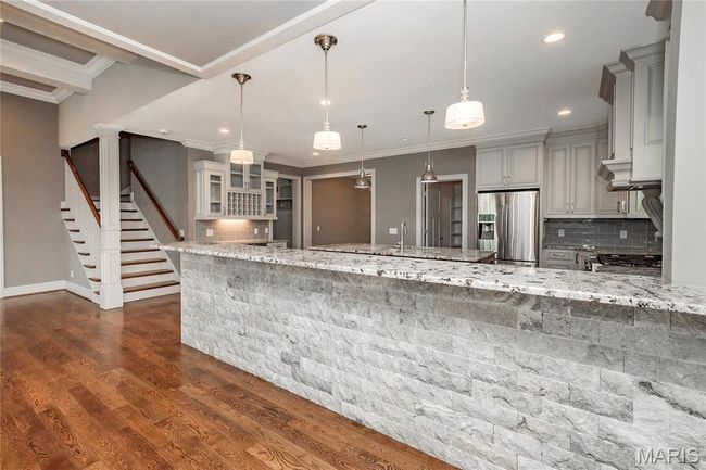 Kitchen featuring stainless steel appliances and breakfast bar, dark wood-style flooring, light stone counters | Image 15