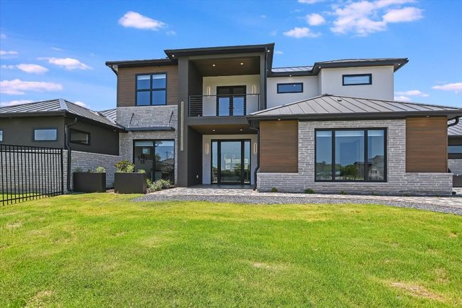 Front view of property featuring a balcony area , a standing seam metal roof, large level yard, brick siding | Image 6