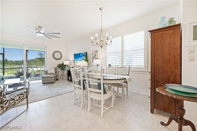 Dining space with healthy amount of natural light, light tile patterned floors, and a chandelier | Image 16