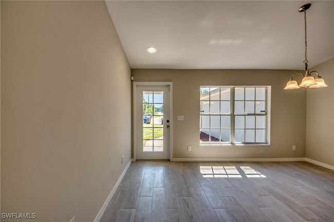 Doorway with wood finished floors, baseboards, and an inviting chandelier | Image 10