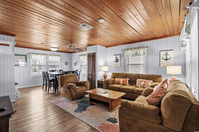 Living room featuring wooden ceiling, wood walls, wood finished floors, ceiling fan, and baseboards | Image 16