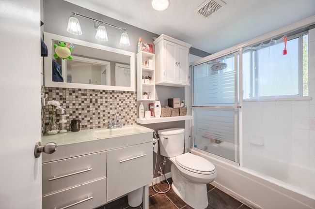 Full bath featuring toilet, vanity, backsplash, visible vents, and shower / bath combination with glass door | Image 11