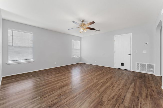 Living room with a ceiling fan, arched walkways, and wood finished floors | Image 7