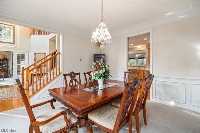 Dining area with ceiling fan with notable chandelier, light carpet, sink, and ornamental molding | Image 14