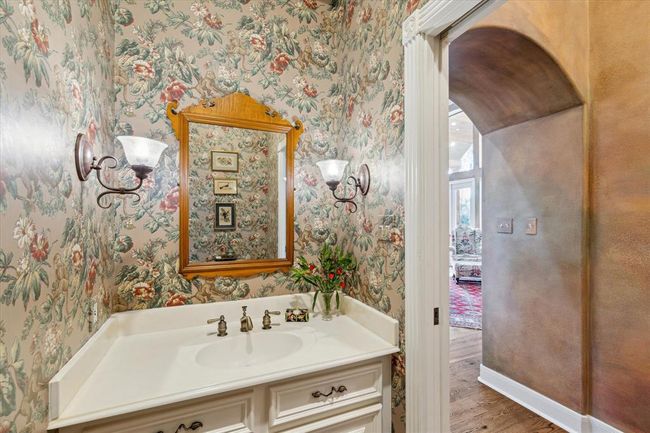 This enchanting powder bathroom boasts character. Charming sconces, wallpaper and classic, sophisticated brass hardware exude style. | Image 16