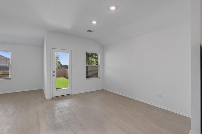 Empty room with light wood-type flooring, lofted ceiling, and recessed lighting | Image 8