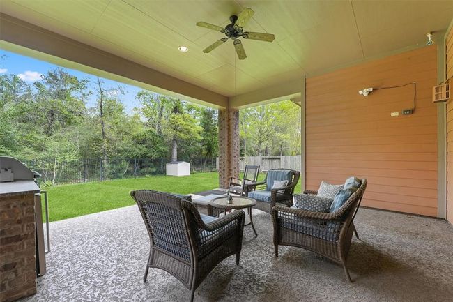 Relax and unwind on the expansive covered patio featuring a ceiling fan and peaceful views of the greenbelt. Perfect for entertaining guests or enjoying quiet evenings outdoors in your private backyard retreat. | Image 32