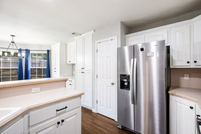 Kitchen featuring stainless steel fridge, a chandelier, white cabinetry, and dark wood-style floors | Image 9