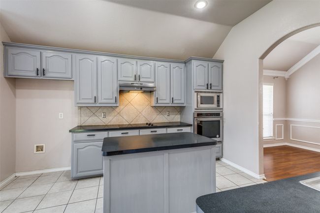 Kitchen featuring dark countertops, lofted ceiling, arched walkways, gray cabinets, and stainless steel appliances | Image 11