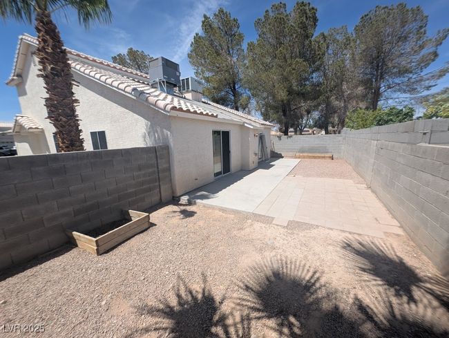 View of side of home featuring a tile roof, a patio area, a fenced backyard, central AC, and stucco siding | Image 9