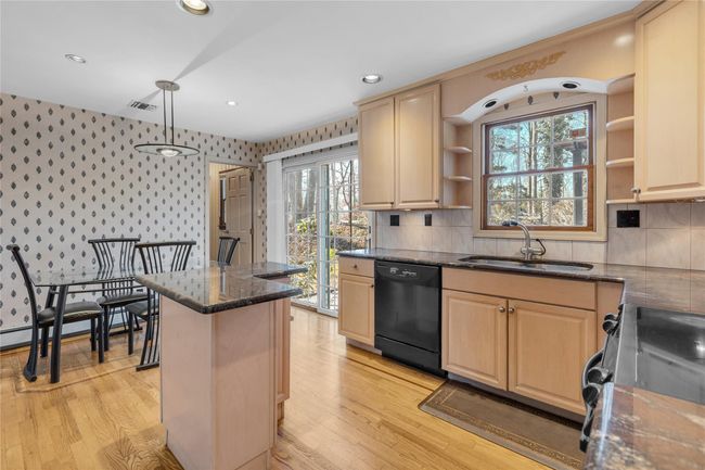 Kitchen with wallpapered walls, black appliances, a sink, and open shelves | Image 8