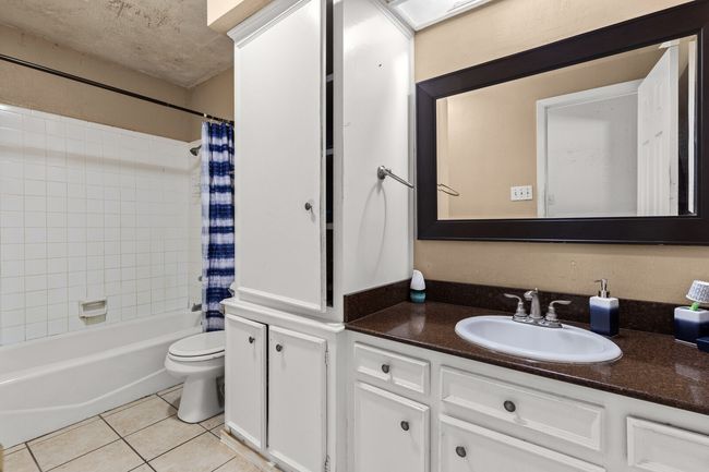 Bathroom featuring shower / bathtub combination with curtain, tile patterned floors, vanity, and toilet | Image 14