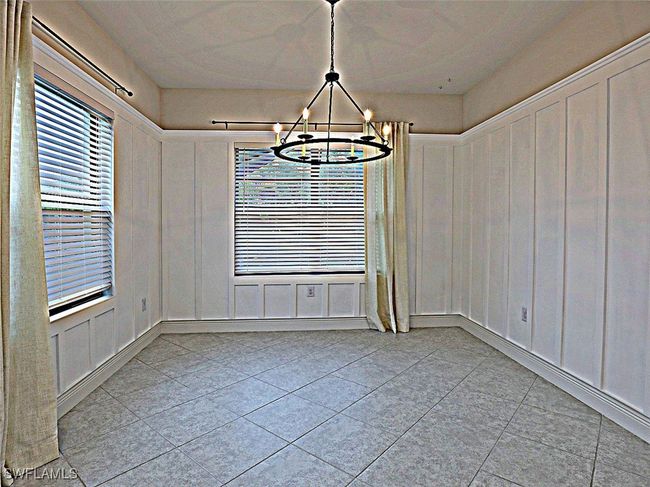 Unfurnished dining area featuring a chandelier, light tile patterned flooring, a decorative wall, and healthy amount of natural light | Image 10
