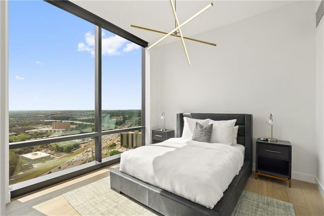 Bedroom with an inviting chandelier, multiple windows, wood finished floors, and expansive windows | Image 13