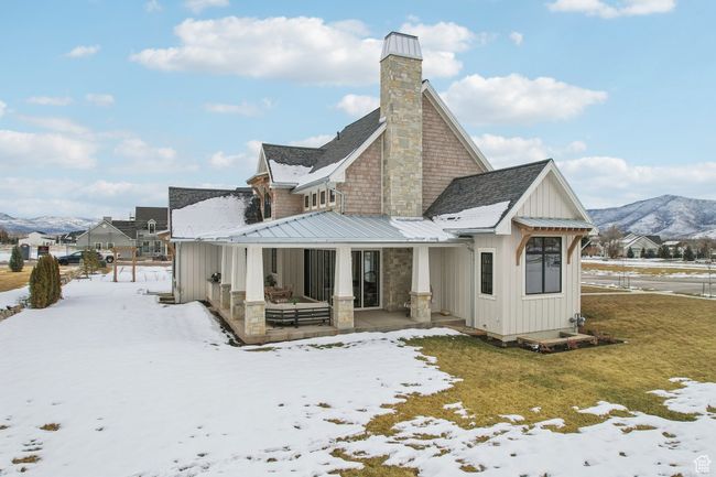 Snow covered back of property featuring roof with shingles, board and batten siding, a standing seam roof, a mountain view, and metal roof | Image 65