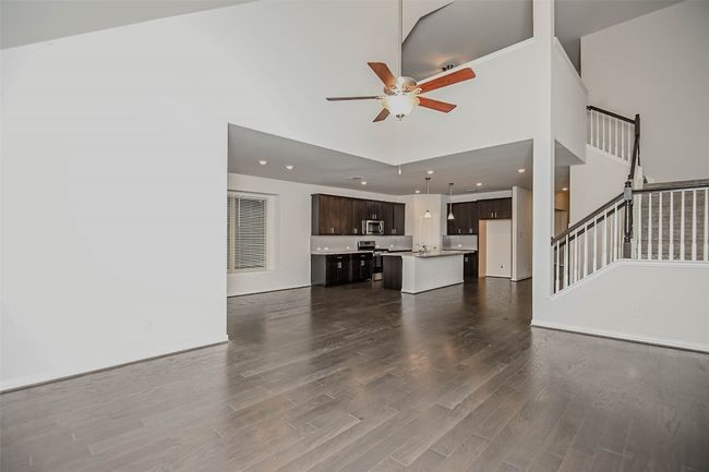 Unfurnished living room featuring stairs, a towering ceiling, recessed lighting, a ceiling fan, and dark wood finished floors | Image 15
