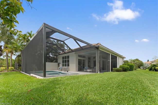 Back of property featuring a lawn, a lanai, stucco siding, an outdoor pool, and a patio area | Image 18