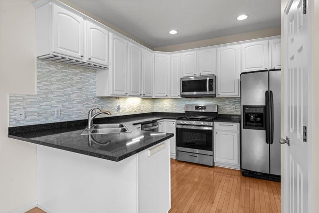 A bright, stylish kitchen with a tile backsplash. | Image 14