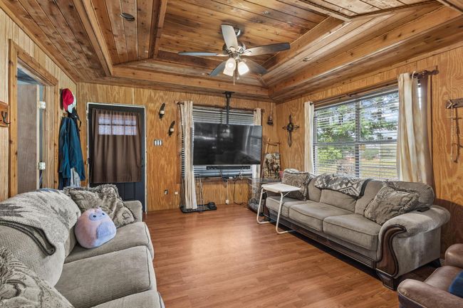 Living room featuring wood ceiling, wood walls, ceiling fan, and wood finished floors | Image 5