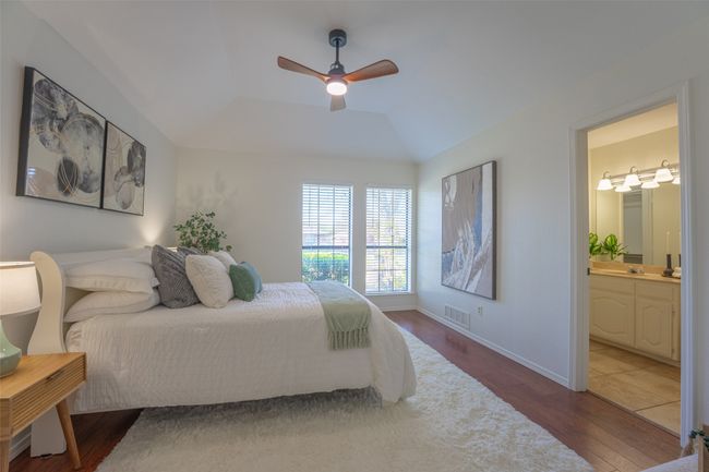 Primary bedroom with ceiling fan, ensuite bathroom, walk-in closet, and wood finished floors | Image 10